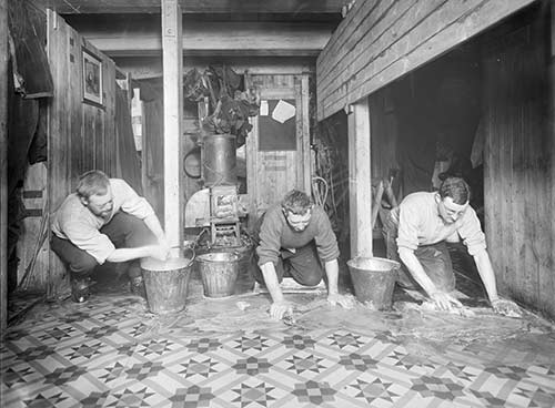 Three men scrubbing the galley floor