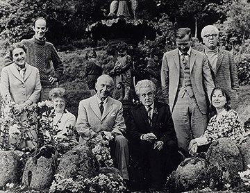 Black and white photograph of eight people in a garden.