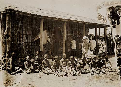 Woman with adults and children outside and African mission