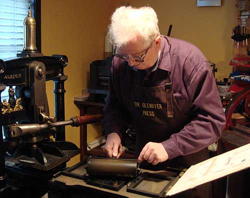 Man at a printing press for miniature books
