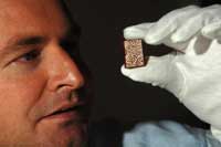 Man holding tiny Qur'an in his white-gloved hand