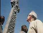 Film still showing three people looking at a stone cross