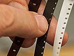 Hand holding three strips of small-gauge film