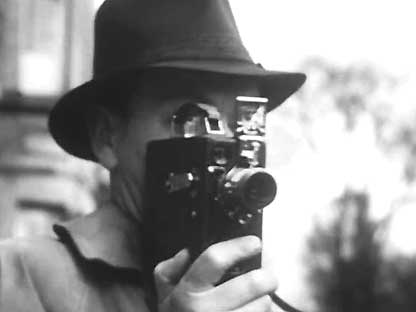 1940s film still of man holding a film camera