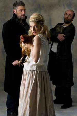 Two men beside a woman holding a hen
