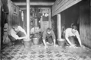 Three men scrubbing the galley floor