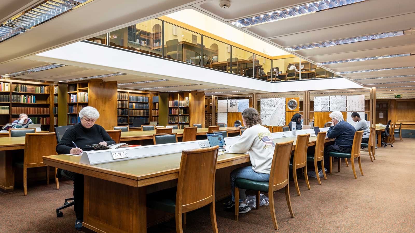Readers seated at a long study desk in a large library space