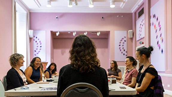 People seated around tables in a meeting room during a group discussion.