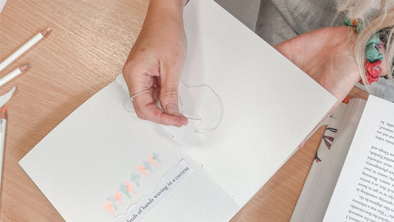 A person threading a zine.