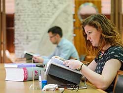 Someone opening a book while sitting at a desk