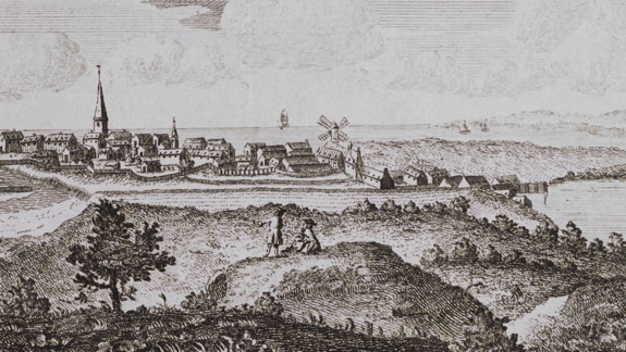 Engraving of a coastal town with a church steeple, windmills, and a ship at sea, viewed from a hill with two figures in the foreground.