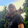 Photo of a man with glasses and a cat on his shoulders.
