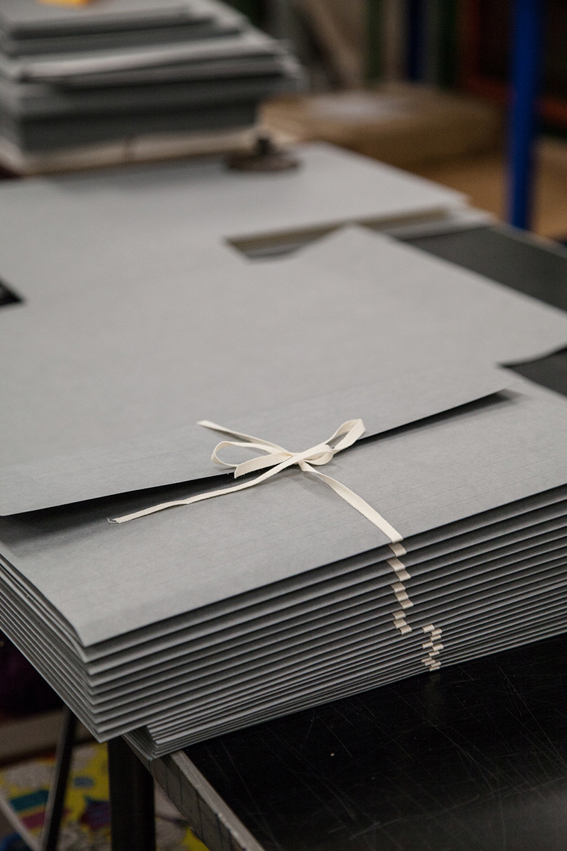 Someone tying thin grey folder closed with cotton tape.