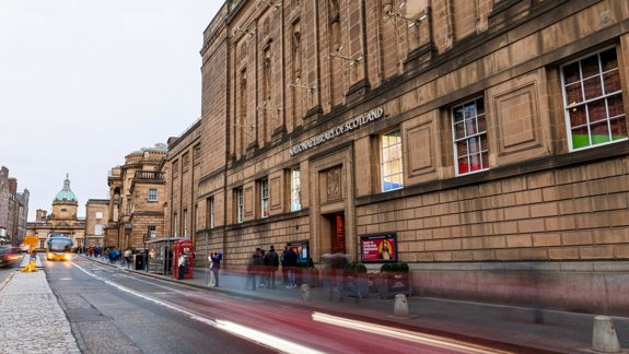 The outside of the Library building on George IV Bridge, also showing the people on the footpath outside and traffic on the road.