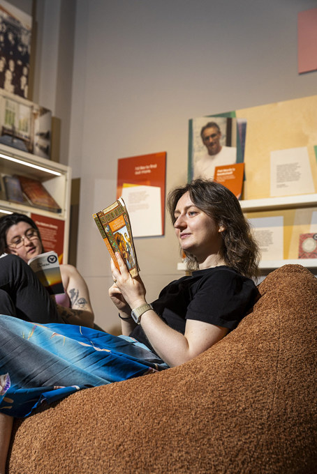 Two people sitting on beanbags reading books.