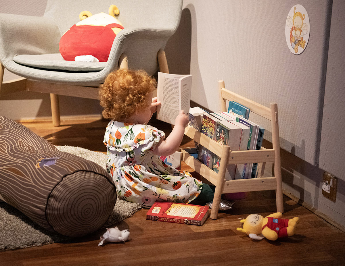 A baby sitting on the floor holding a book.