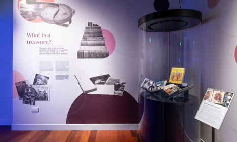 An exhibition panel describing what a treasure is and a round exhibition case next to it showing home shopping catalogues.