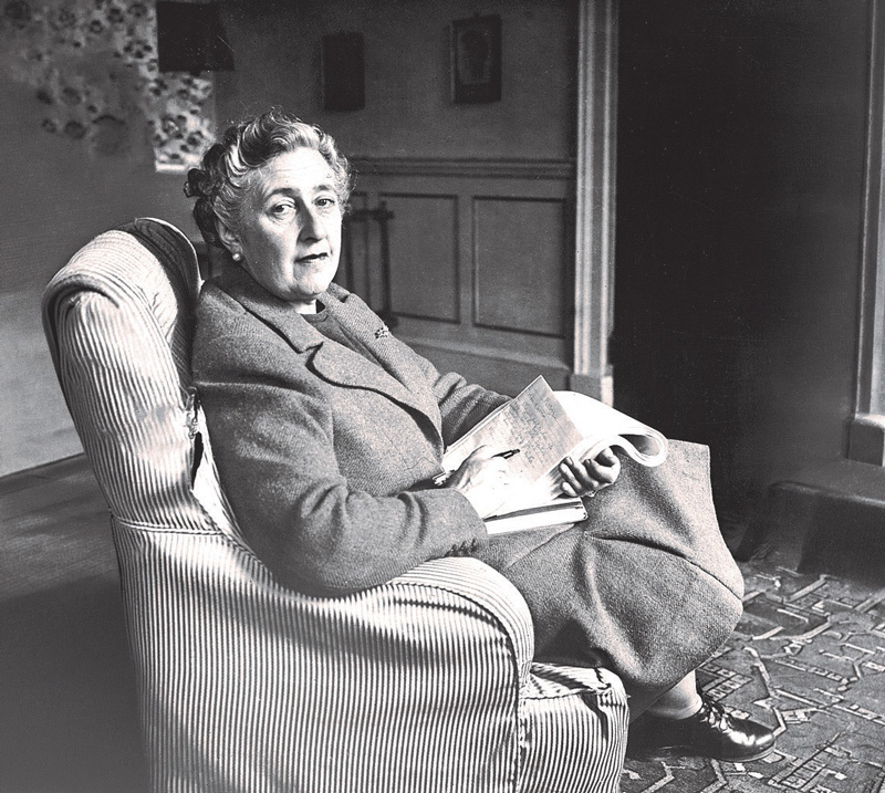 Agatha Christie sitting in a chair with notes in her lap.
