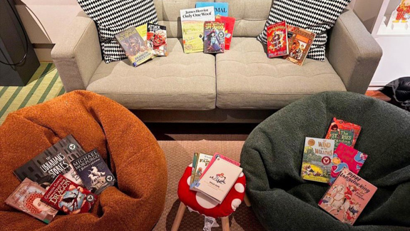 A couch and too beanbags covered in books.