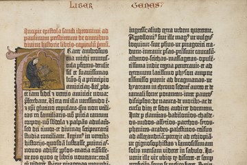 A photo of the first page of the Gutenberg Bible. It is in an old fashioned script and has an illustration of someone sitting at a desk writing in the top left corner.