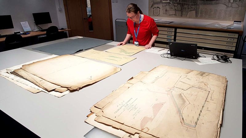 A visitor looks at a large old map on a big table in the maps reading room