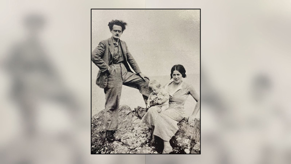 Hugh MacDiarmid standing on a rock in Whalsay next to Valda Grieve who is sitting and holding their baby Michael.