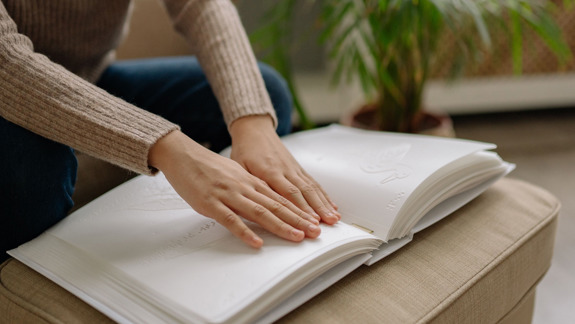 A person touching an embossed book with braille.