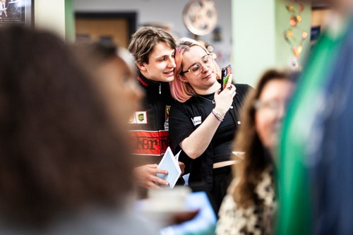 One person leaning against another amongst a crowd in the Moving Image Archive access centre.