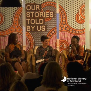Three women sitting in chairs speaking. They are facing an audience. Behind them is a banner that says "Our Stories Told by Us" with a colourful swirl pattern behind it. There is a white National Library of Scotland logo in the bottom right..