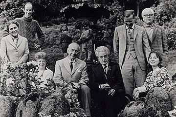 Black and white photograph of eight people in a garden.