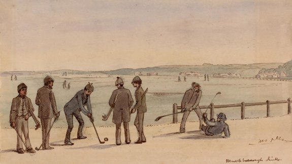 A group of men playing golf on a course with rolling hills and buildings in the background.