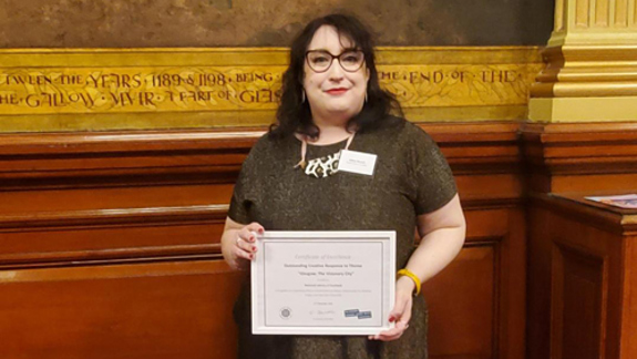 Gillian Russell standing and holding a certificate.