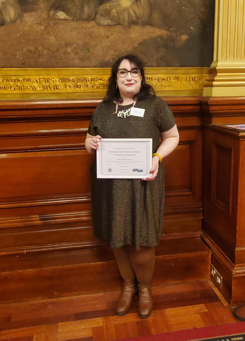 Gillian Russell standing and holding a certificate.