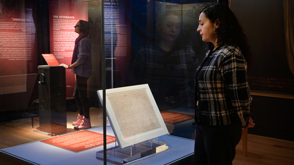 A visitor standing in an exhibition space looking at Mary Queen of Scot's last letter on display.