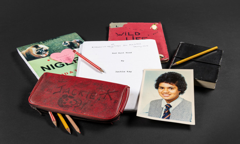 Ephemera from Jackie Kay's archive including a pencil case, notebooks, and a school photo.
