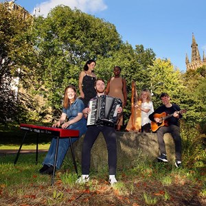 Six members of the band Duan pose for a photo in Kelvingrove Park, Glasgow. They are playing various instruments.