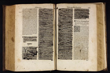 An old open book that has had sections crossed out with black ink.