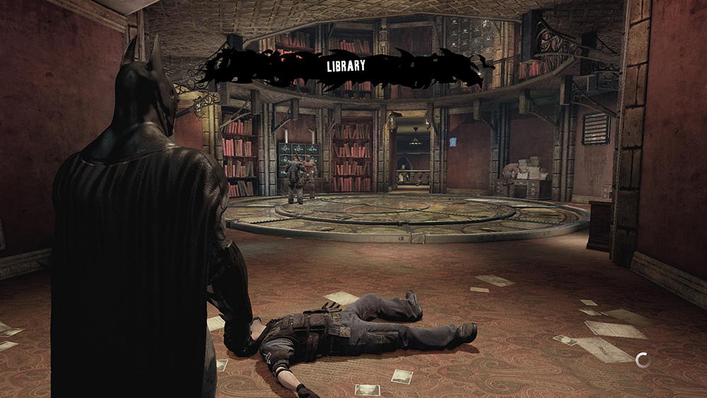 Batman looks across a damaged circular library with scattered papers, bookshelves, and an unconscious figure on the floor.
