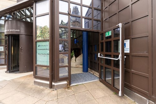 The outside accessible entrance to Causewayside. The door is opened outwards and covers the intercom which is on the wall.