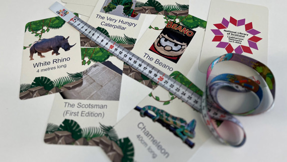National Library of Scotland branded playing cards with pictures of collections items on them and a tape measure.