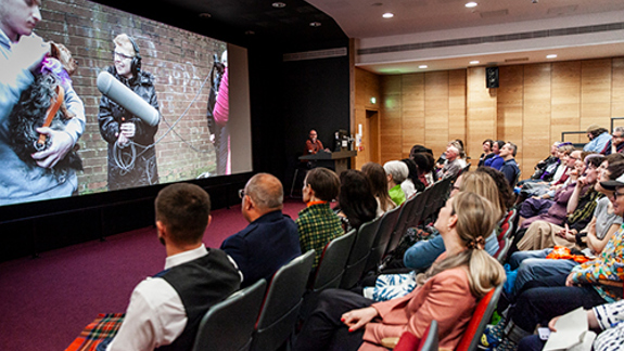 Audience watching a film screening in a lecture theatre with a large screen.