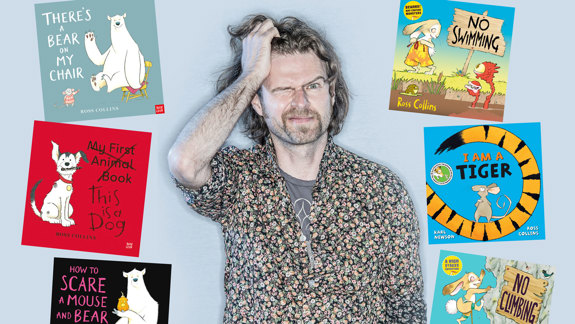 A man looking at the camera surrounded by books for children.