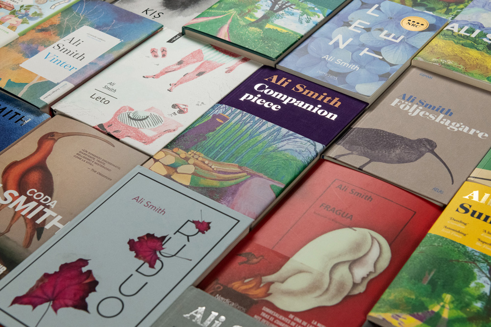 Lots of books by Ali Smith spread out on a table.