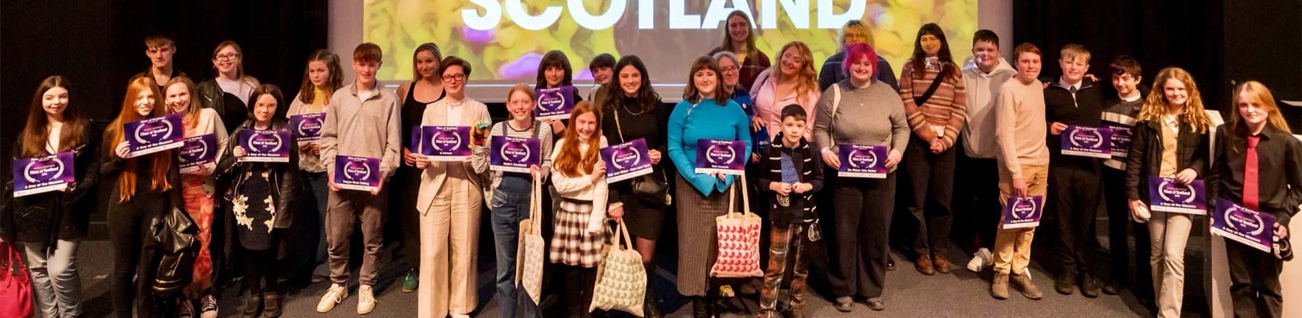 Competition winners stand on a stage holding certificates
