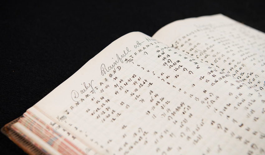 An open book of handwritten rainfall statistics.