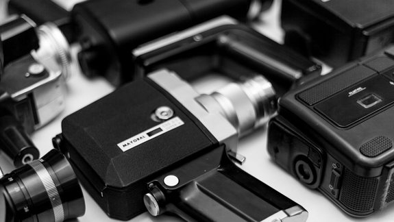 Black and white photo of vintage video cameras lying on their side.