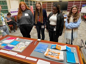 Four girls stand in front of a table that is displaying archival material.
