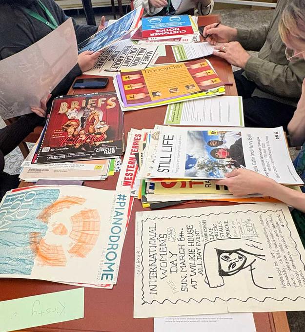 People browsing a selection of historical Scottish posters.