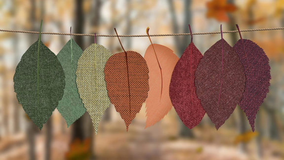 Eight autumn-coloured leaves made out of fabric hanging on a string.