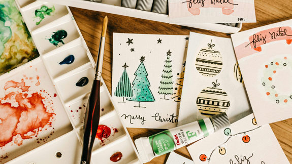 A paint brush sitting on top of a paint tray and a selection of Christmas cards lying on a table.